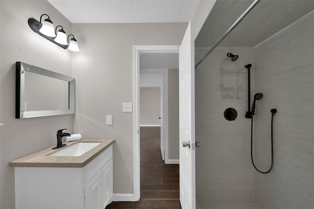 bathroom with a tile shower, a textured ceiling, hardwood / wood-style flooring, and vanity