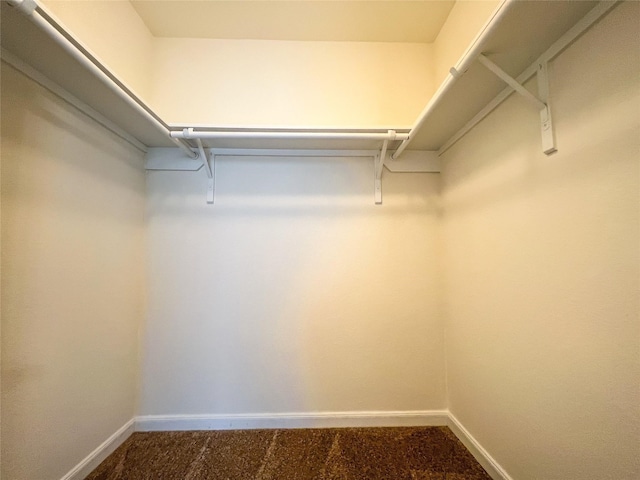 walk in closet featuring dark carpet