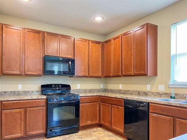 kitchen featuring a textured ceiling, black appliances, and a wealth of natural light