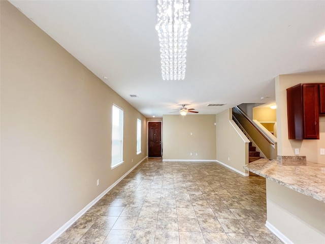 unfurnished living room featuring ceiling fan with notable chandelier