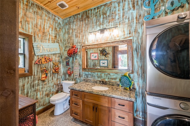 bathroom featuring vanity, toilet, stacked washer and clothes dryer, and wooden ceiling