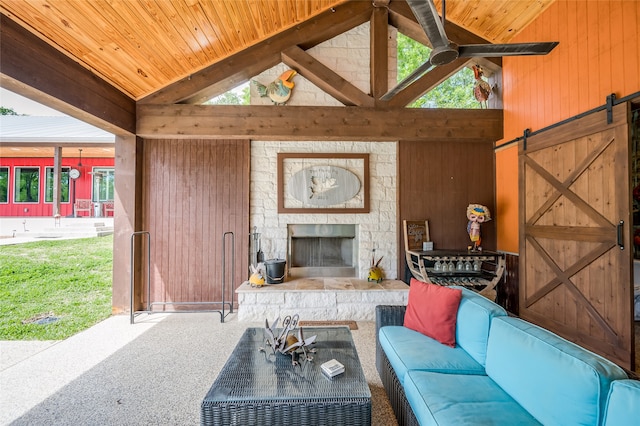 carpeted living room with a stone fireplace, a barn door, high vaulted ceiling, wooden walls, and wooden ceiling