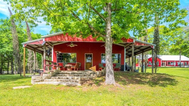 rear view of property with ceiling fan, a lawn, and covered porch