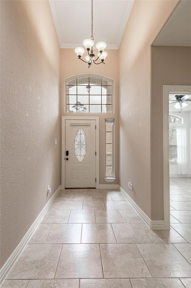 entrance foyer with a wealth of natural light, ceiling fan with notable chandelier, and crown molding