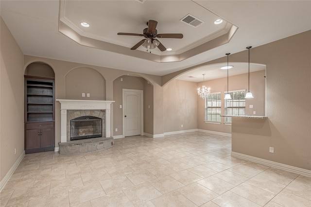 unfurnished living room featuring ceiling fan with notable chandelier, a raised ceiling, and ornamental molding