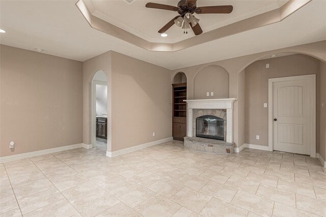 unfurnished living room with ornamental molding, ceiling fan, a raised ceiling, and a tile fireplace