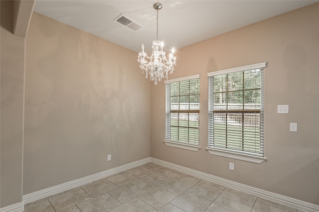 tiled empty room featuring a chandelier