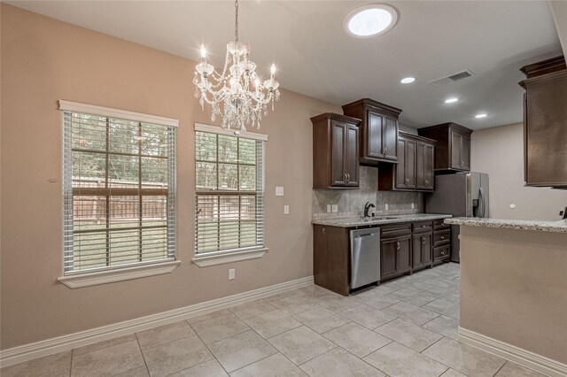 kitchen featuring backsplash, appliances with stainless steel finishes, decorative light fixtures, and a healthy amount of sunlight