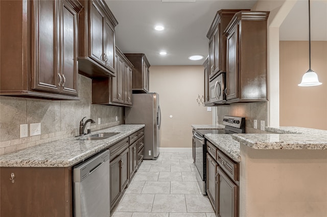 kitchen featuring stainless steel appliances, light stone countertops, hanging light fixtures, decorative backsplash, and sink