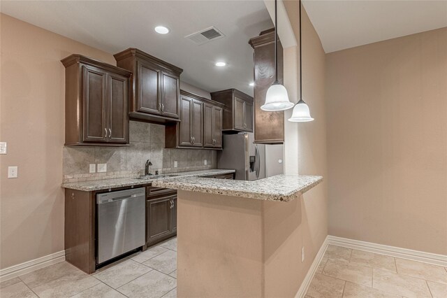 kitchen featuring tasteful backsplash, appliances with stainless steel finishes, light stone countertops, hanging light fixtures, and kitchen peninsula