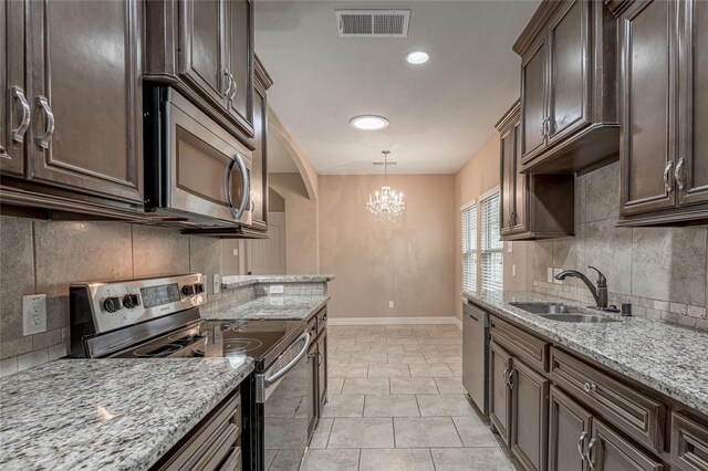 kitchen with stainless steel appliances, sink, light stone countertops, hanging light fixtures, and decorative backsplash