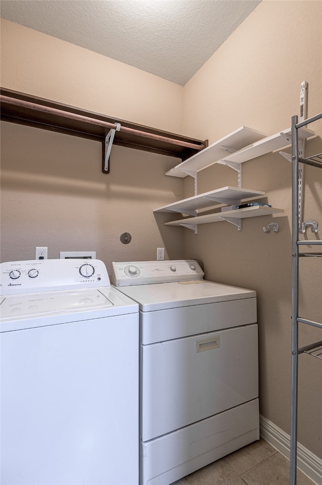 laundry area featuring washer and clothes dryer, a textured ceiling, and light tile patterned floors