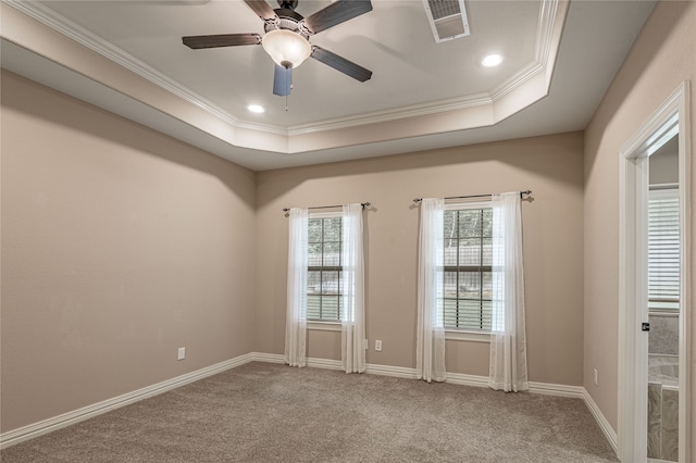 empty room with ornamental molding, carpet floors, ceiling fan, and a raised ceiling