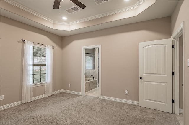 empty room featuring ceiling fan, a tray ceiling, light colored carpet, and ornamental molding