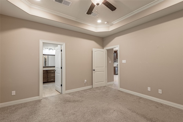 unfurnished bedroom with connected bathroom, light carpet, crown molding, and a tray ceiling