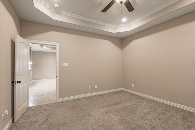 carpeted empty room with ceiling fan, a raised ceiling, and ornamental molding