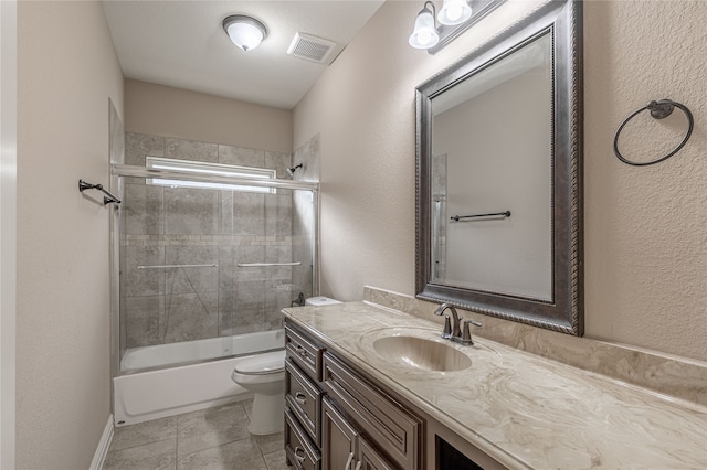 full bathroom with tile patterned floors, vanity, combined bath / shower with glass door, and toilet