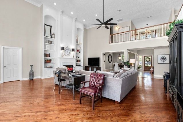 living room with a textured ceiling, a high ceiling, dark hardwood / wood-style floors, and built in shelves