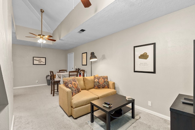 living room featuring ceiling fan, a textured ceiling, vaulted ceiling, and light colored carpet