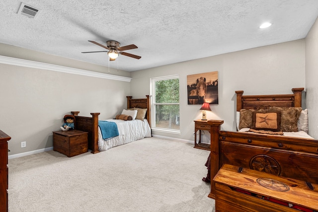 bedroom with ceiling fan, light carpet, and a textured ceiling