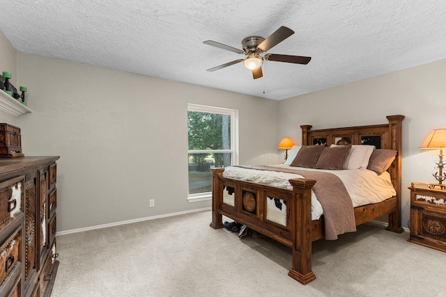 bedroom featuring a textured ceiling, light colored carpet, and ceiling fan