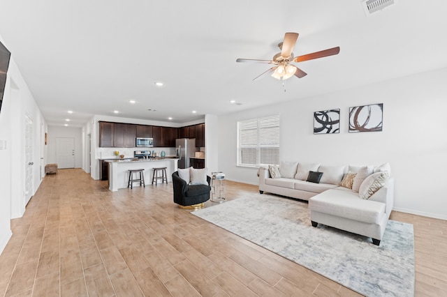 living room with light wood-type flooring and ceiling fan