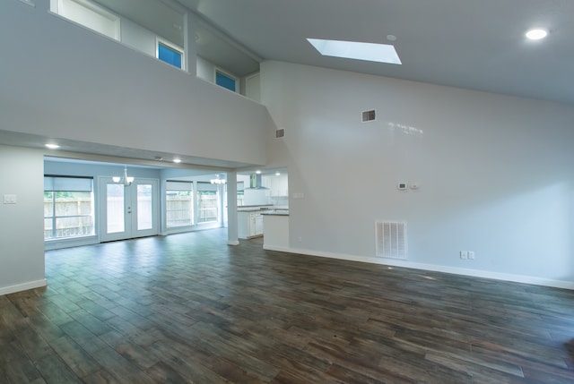 unfurnished living room with high vaulted ceiling, a skylight, and dark hardwood / wood-style flooring