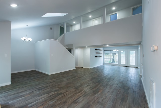 unfurnished living room with french doors, dark wood-type flooring, a chandelier, high vaulted ceiling, and a skylight