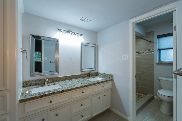 bathroom with toilet, vanity, and a tile shower