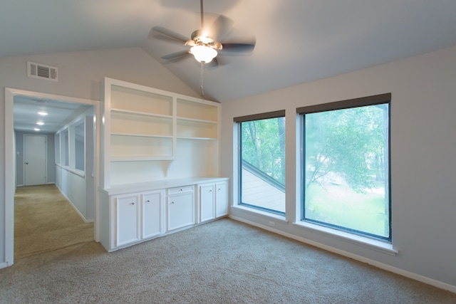 unfurnished living room with ceiling fan, a healthy amount of sunlight, vaulted ceiling, and light colored carpet