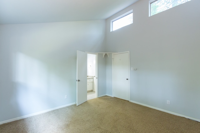 carpeted empty room with high vaulted ceiling