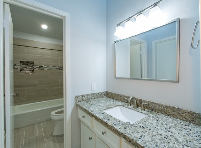 full bathroom with tiled shower / bath, vanity, and toilet