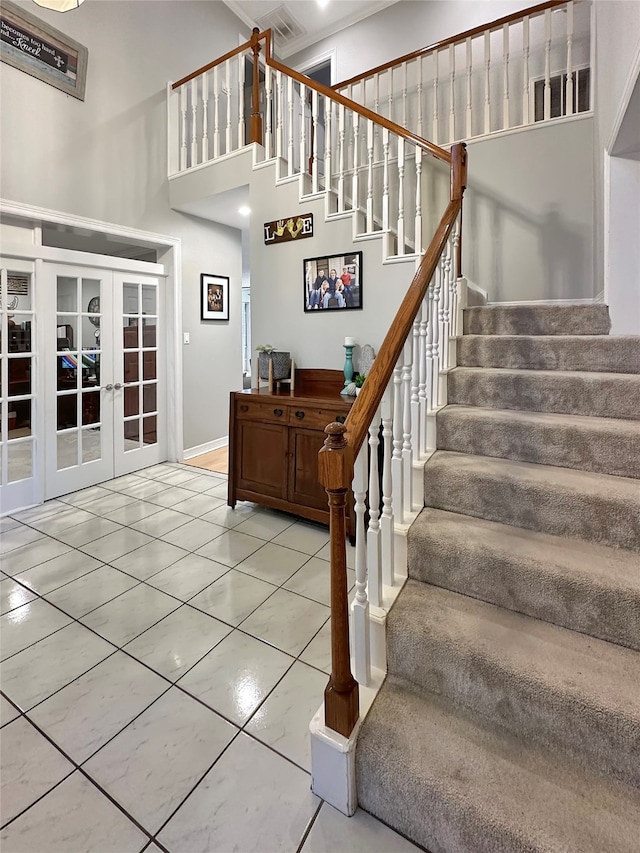 staircase with tile patterned flooring, a high ceiling, french doors, and ornamental molding