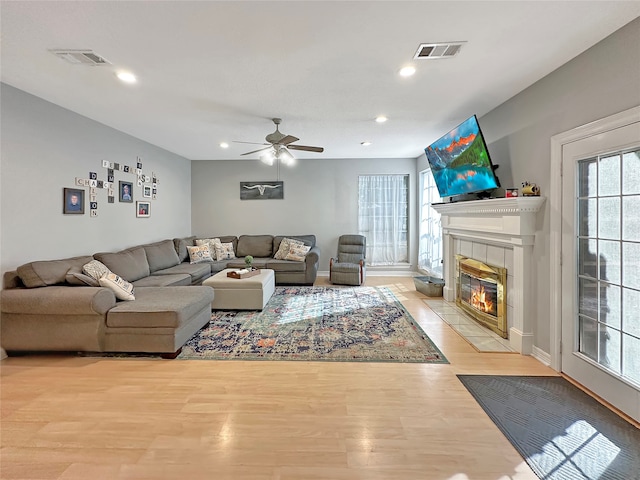 living room with a fireplace, a wealth of natural light, light hardwood / wood-style flooring, and ceiling fan