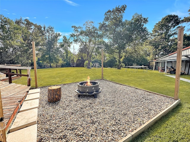 view of yard with a deck, a fire pit, and a trampoline