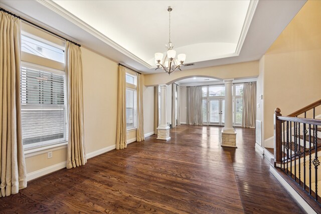 foyer featuring dark wood-type flooring, a notable chandelier, decorative columns, crown molding, and a raised ceiling