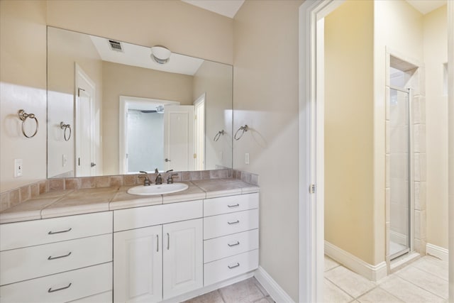 bathroom featuring a shower with shower door, vanity, and tile patterned floors