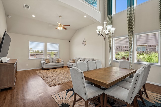 dining space with hardwood / wood-style floors, ceiling fan with notable chandelier, and high vaulted ceiling