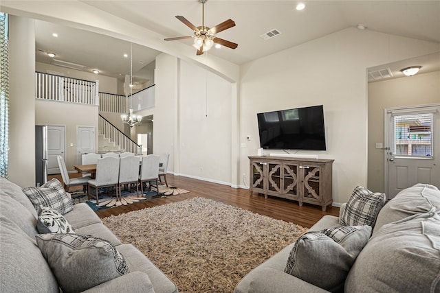 living room with ceiling fan with notable chandelier, dark hardwood / wood-style flooring, and high vaulted ceiling