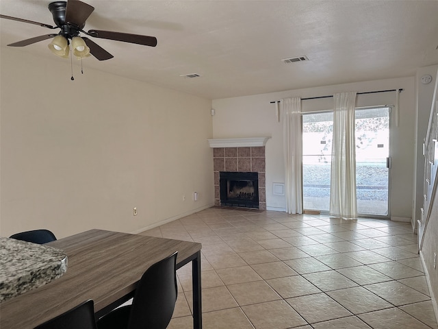 tiled living room featuring ceiling fan and a fireplace