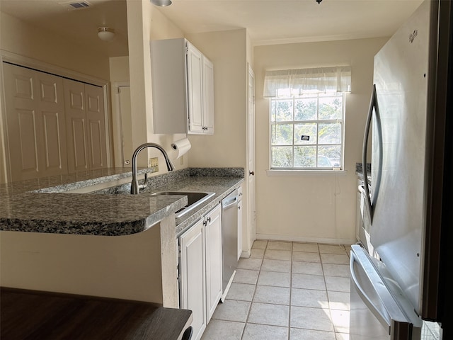 kitchen featuring kitchen peninsula, white cabinetry, light tile patterned flooring, sink, and stainless steel appliances