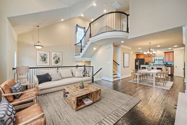 living room with dark wood-type flooring, a notable chandelier, high vaulted ceiling, and ornamental molding