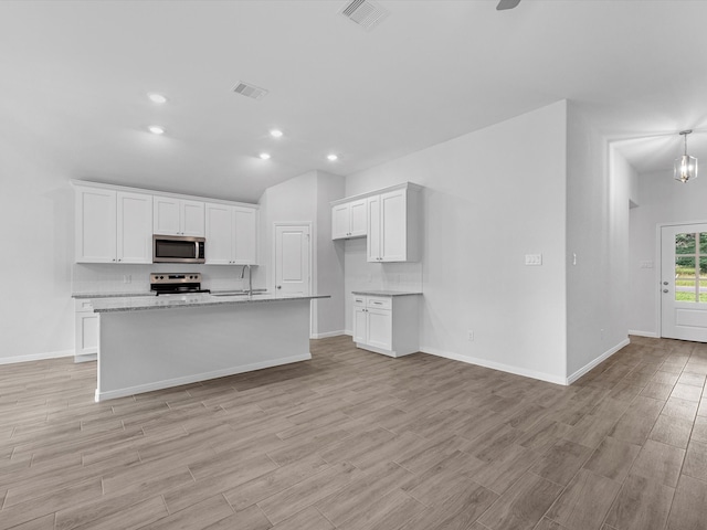 kitchen with a center island with sink, light stone counters, white cabinetry, light hardwood / wood-style floors, and stainless steel appliances