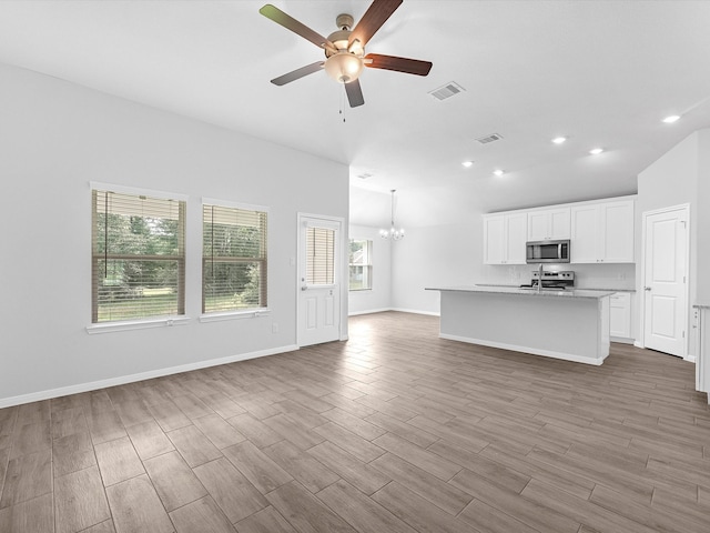 unfurnished living room featuring light wood-type flooring and ceiling fan with notable chandelier