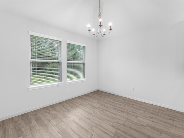 empty room featuring light hardwood / wood-style flooring and a notable chandelier