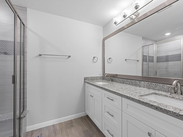 bathroom featuring vanity, hardwood / wood-style floors, a shower with shower door, and a textured ceiling