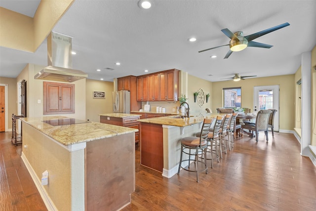 kitchen featuring stainless steel fridge, dark hardwood / wood-style flooring, a center island, and island range hood