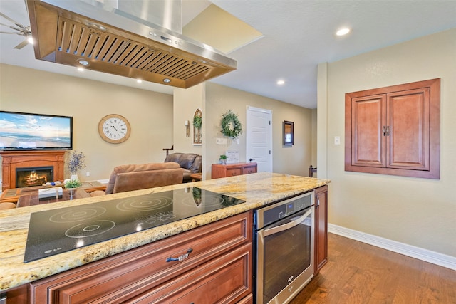 kitchen featuring island exhaust hood, light stone countertops, black electric cooktop, dark hardwood / wood-style floors, and oven