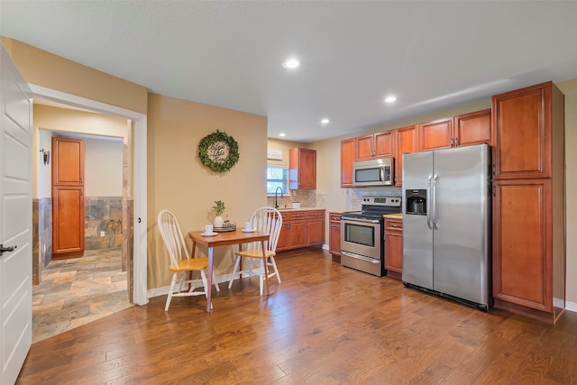 kitchen with wood-type flooring, appliances with stainless steel finishes, decorative backsplash, and sink