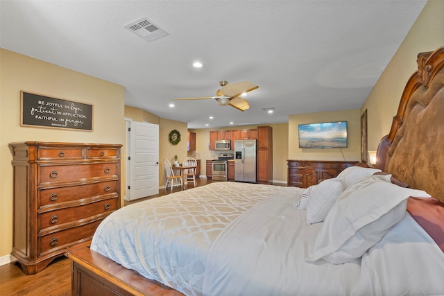 bedroom featuring ceiling fan, stainless steel fridge, and light hardwood / wood-style floors